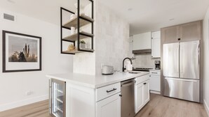 A modern kitchen with white cabinetry, a stainless steel refrigerator, and a built-in dishwasher. - Ultra-Clean, Designer Condo in Downtown Scottsdale (Scottsdale)