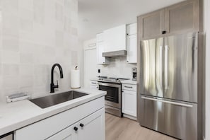 A modern kitchen with white cabinetry, stainless steel appliances, and a double sink.
