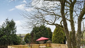 A fenced garden area with a picnic table and a red umbrella.