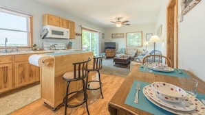 A kitchen with wooden cabinets, a microwave, and a dining area with a table set for four. - Lakefront Cozy Cabin w/ Dock; 2 BR- 1BA, One Hour from the Twin Cities (Lindstrom)