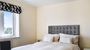 A bedroom with a bed, a nightstand, a radiator, and a window with a black and white valance. - 2 bedroom accommodation in Silsden, near Keighley (Silsden, near Keighley)