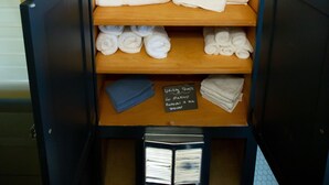 Ein Badezimmerschrank mit Regalen, der Toilettenartikel, Handtücher und ein Schild zur Kennzeichnung der Handtuchnutzung enthält.
