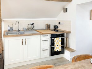 A modern kitchen with white cabinets, a double sink, a wooden countertop, and a built-in oven.