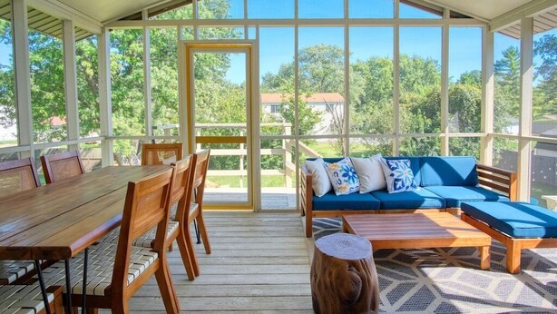 A covered patio with a wooden table, chairs, and a blue sofa with cushions. - Modern-Sunroom-15min to DwnTwn-Grps-Kids-Firepit (Indianapolis)