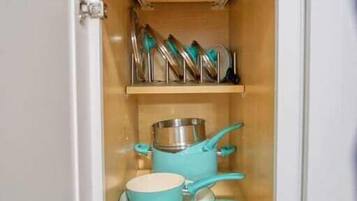 Un armario de cocina con ollas y sartenes.