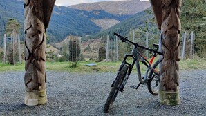 Un vélo tout-terrain appuyé contre une structure en bois, avec en arrière-plan un paysage montagneux.