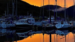 Un port de plaisance où de nombreux bateaux sont amarrés au coucher du soleil.