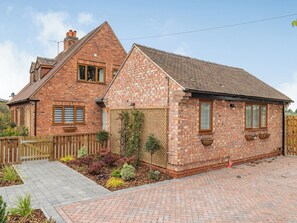 A two-story brick house with a sloped roof, a wooden fence, and a landscaped garden. - 4 bedroom accommodation in Church Broughton, near Derby (Church Broughton, near Derby)