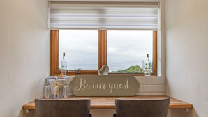 A room with a wooden desk, two chairs, a window with a view, and a sign that reads "Be our guest". - 4 bedroom accommodation in Church Broughton, near Derby (Church Broughton, near Derby)