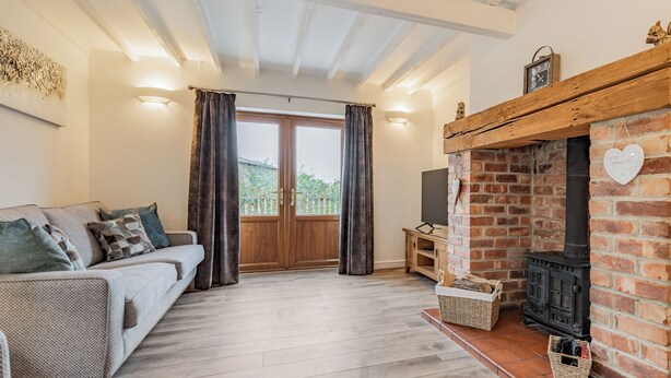 A cozy living room with a sofa, curtains, a fireplace, and a TV. - 4 bedroom accommodation in Church Broughton, near Derby (Church Broughton, near Derby)