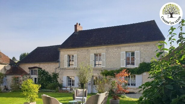 A stone house with a well-maintained lawn and outdoor seating area. - Charming gîte with garden and fireplace (Neuilly-en-Vexin)