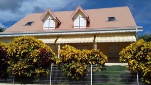 Ein zweistöckiges Haus mit Giebeldach, einem Balkon und einer Veranda.