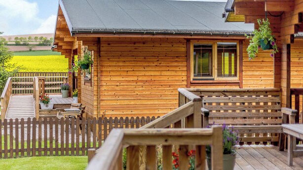 A wooden cabin with a deck, a window, and a fence.