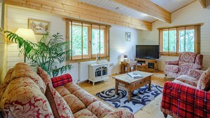 A cozy living room with wooden walls, a fireplace, a television, and a large plant.