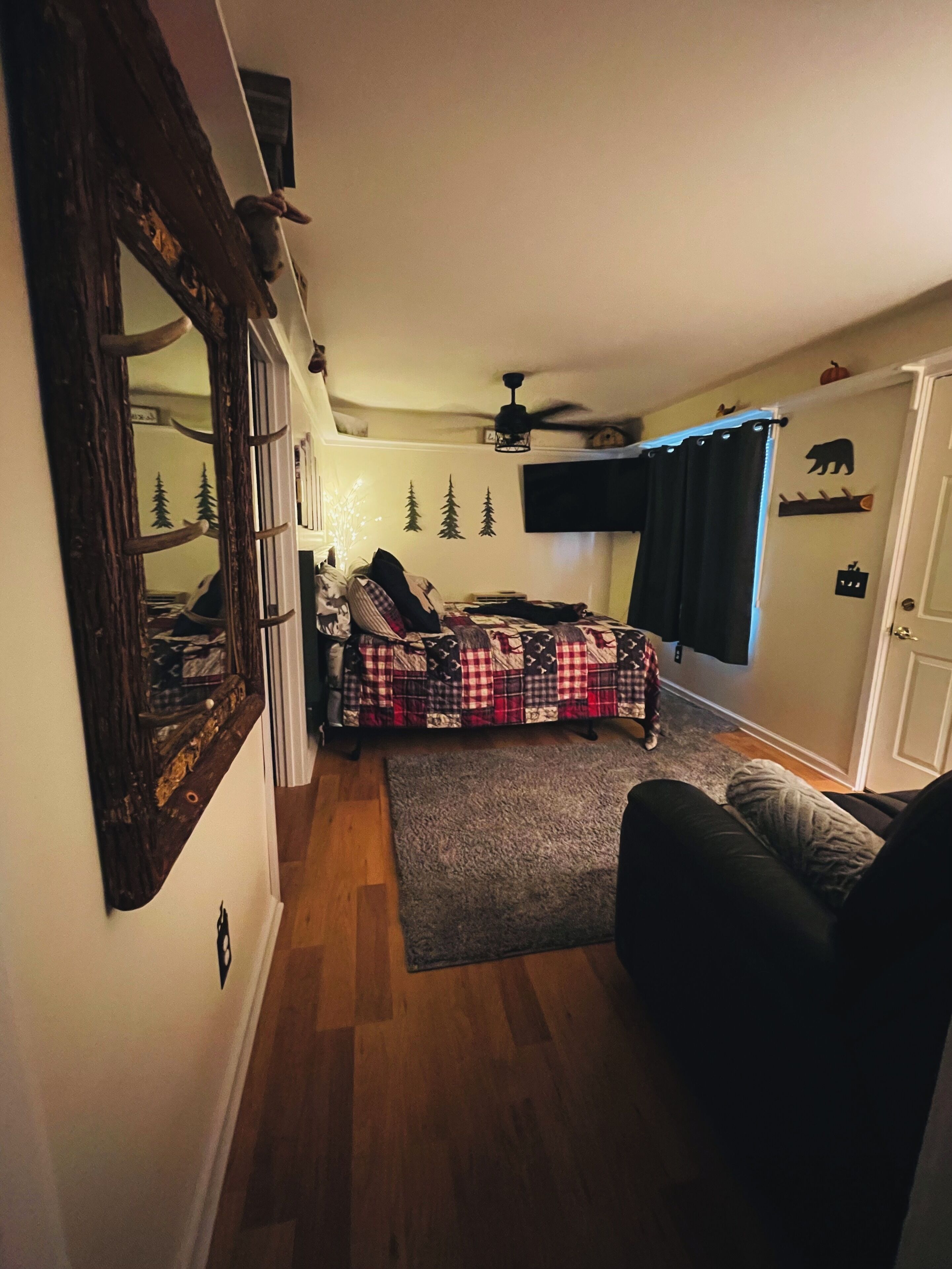 A cozy bedroom with a bed, a chair, a rug, and a ceiling fan.