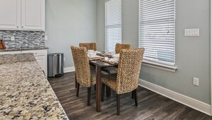 A dining area with a granite countertop, dark wood flooring, wicker chairs, and a table set for four. - Hook Wine & Sinker Lodge at Hackberry  (Hackberry)