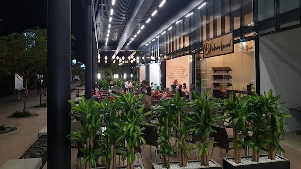 Een buitenterras met tafels en stoelen, omringd door potplanten.