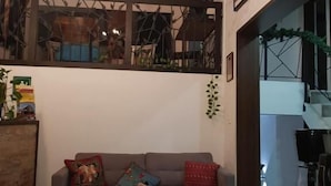 Een gezellige woonkamer met een bank, een kamerkleed, inbouwspots en kunstwerken aan de muren.