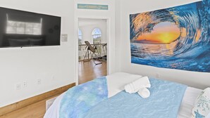 Una camera da letto con un letto, una televisione e un grande quadro raffigurante un'onda.