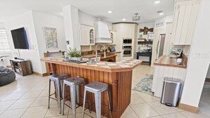 Una cucina moderna con isola centrale, sgabelli da bar, lavello e cestino.