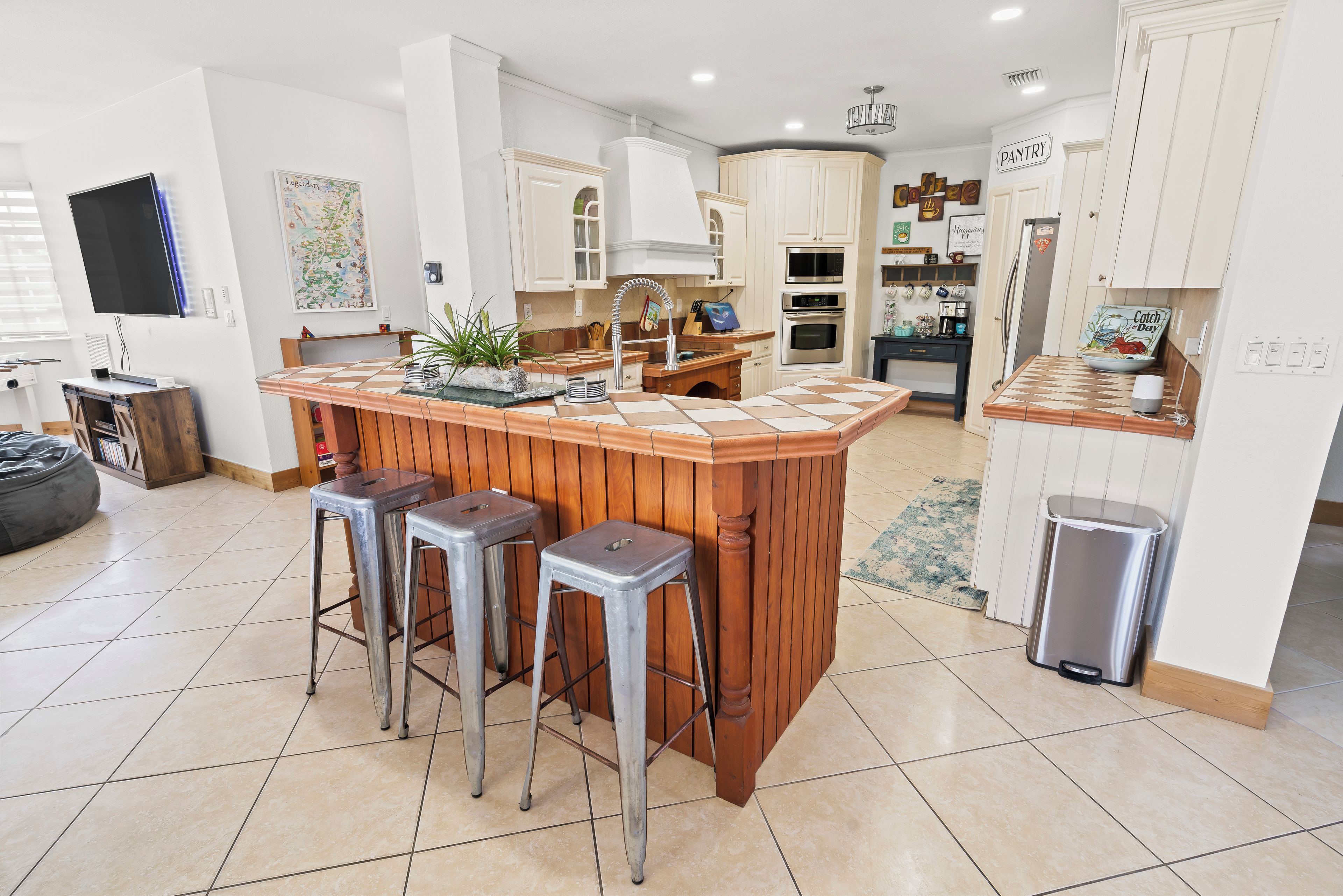 Una cocina moderna con una isla central, taburetes de bar, un lavamanos y un cubo de basura.