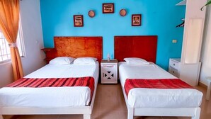 A room with two beds, a blue wall, and a red headboard.