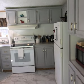 Une cuisine avec des meubles de couleur grise, une cuisinière blanche et un réfrigérateur.