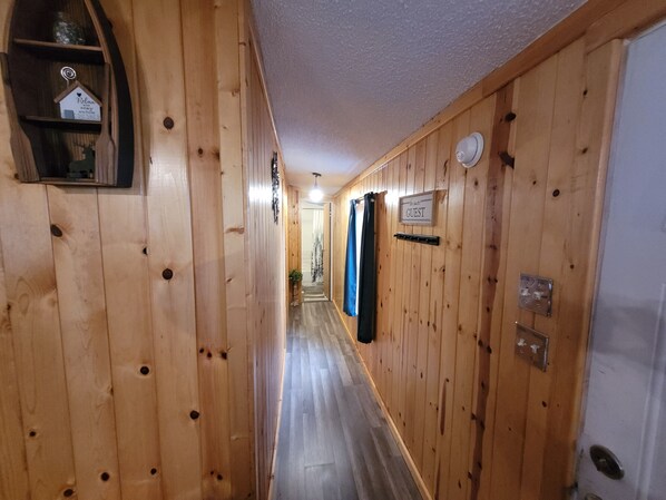 A wooden hallway with a sign reading "GUEST" and a small shelf with a decorative item.