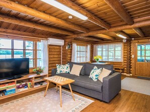 A cozy log cabin interior with a sofa, television, and bookshelves. - Mäntyranta by Interhome (Savonlinna)