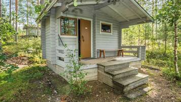 A small cabin with a wooden door, a window, and a bench outside.