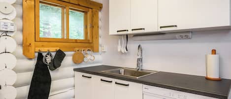 A compact kitchen with white cabinets, a stainless steel sink, and a window above the sink.