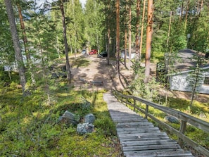 A wooden deck leading to a campsite surrounded by tall pine trees. - Mäntyranta by Interhome (Savonlinna)