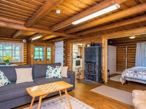 Ein gemütliches Blockhaus-Interieur mit einer Couch, einem Schachtisch, einem Kamin und einem Bett.