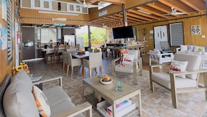 A spacious covered patio area with wooden flooring, multiple seating arrangements, a kitchen area, and a dining table. - Casa Garito La Parguera - Home for up to 24 guests (La Parguera)