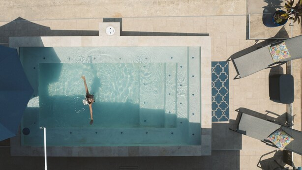 An aerial view of a swimming pool with a person in the water, surrounded by lounge chairs and a small table with a plant. - Casa Garito La Parguera - Home for up to 24 guests (La Parguera)