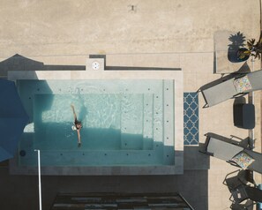 An aerial view of a swimming pool with a person in the water, surrounded by lounge chairs and a small table with a plant. - Casa Garito La Parguera - Home for up to 24 guests (La Parguera)