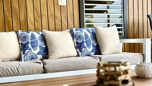 A wooden wall with a 'BEACH' sign, a white sofa with blue patterned pillows, and a wooden coffee table with starfish and a stack of logs. - Casa Garito La Parguera - Home for up to 24 guests (La Parguera)
