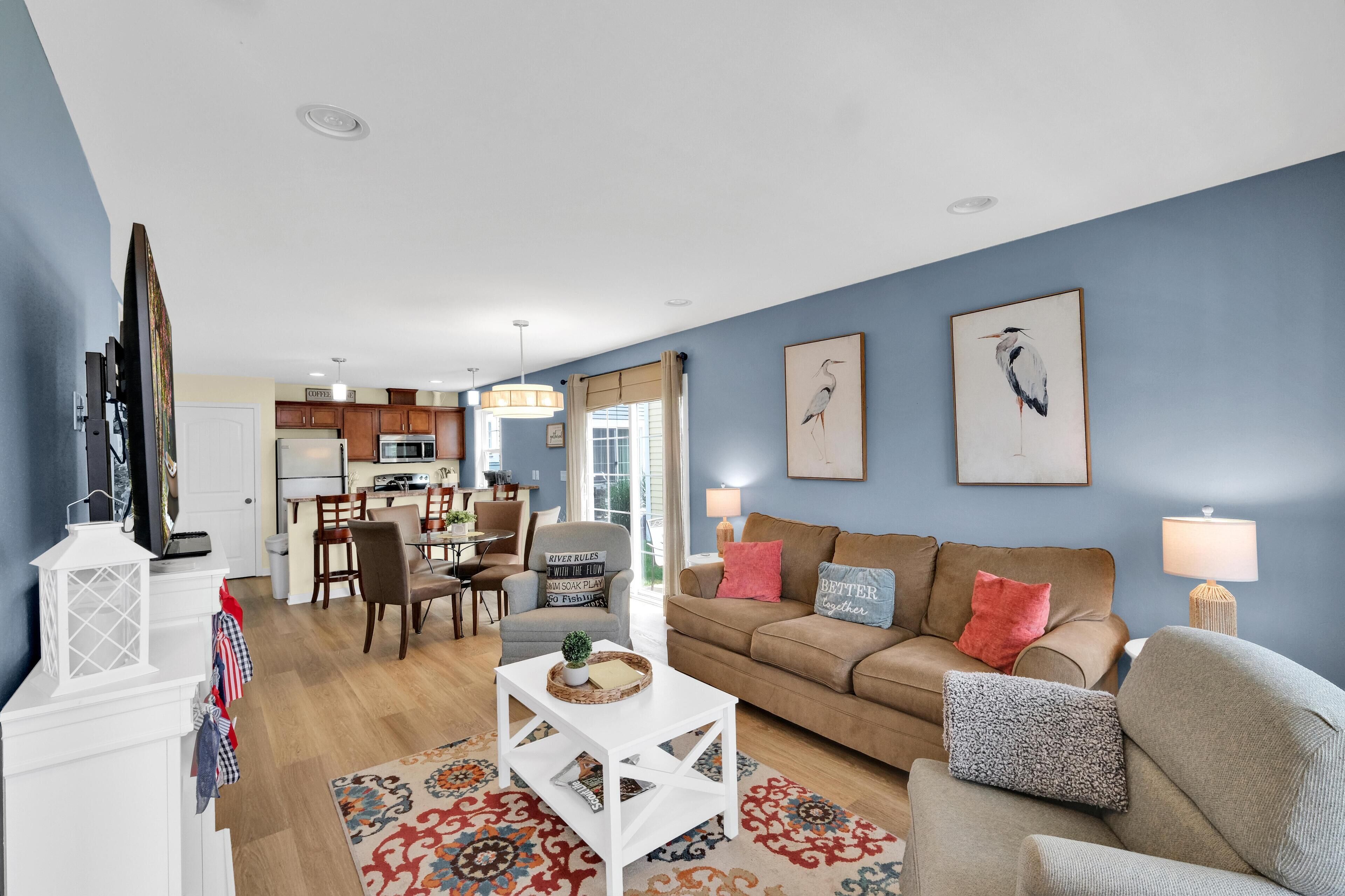 A living room with a sofa, coffee table, and a dining area with chairs and a table.