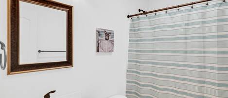 A bathroom with a white sink, a mirror with a wooden frame, a toilet, and a striped shower curtain.