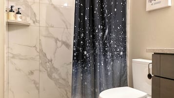 Een bad/douchecombinatie, een haardroger, handdoeken, zeep