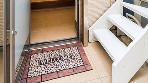 Ein Hotel Eingang mit Glastür, Fußmatte und einer Treppe, die zu einer oberen Etage führt.