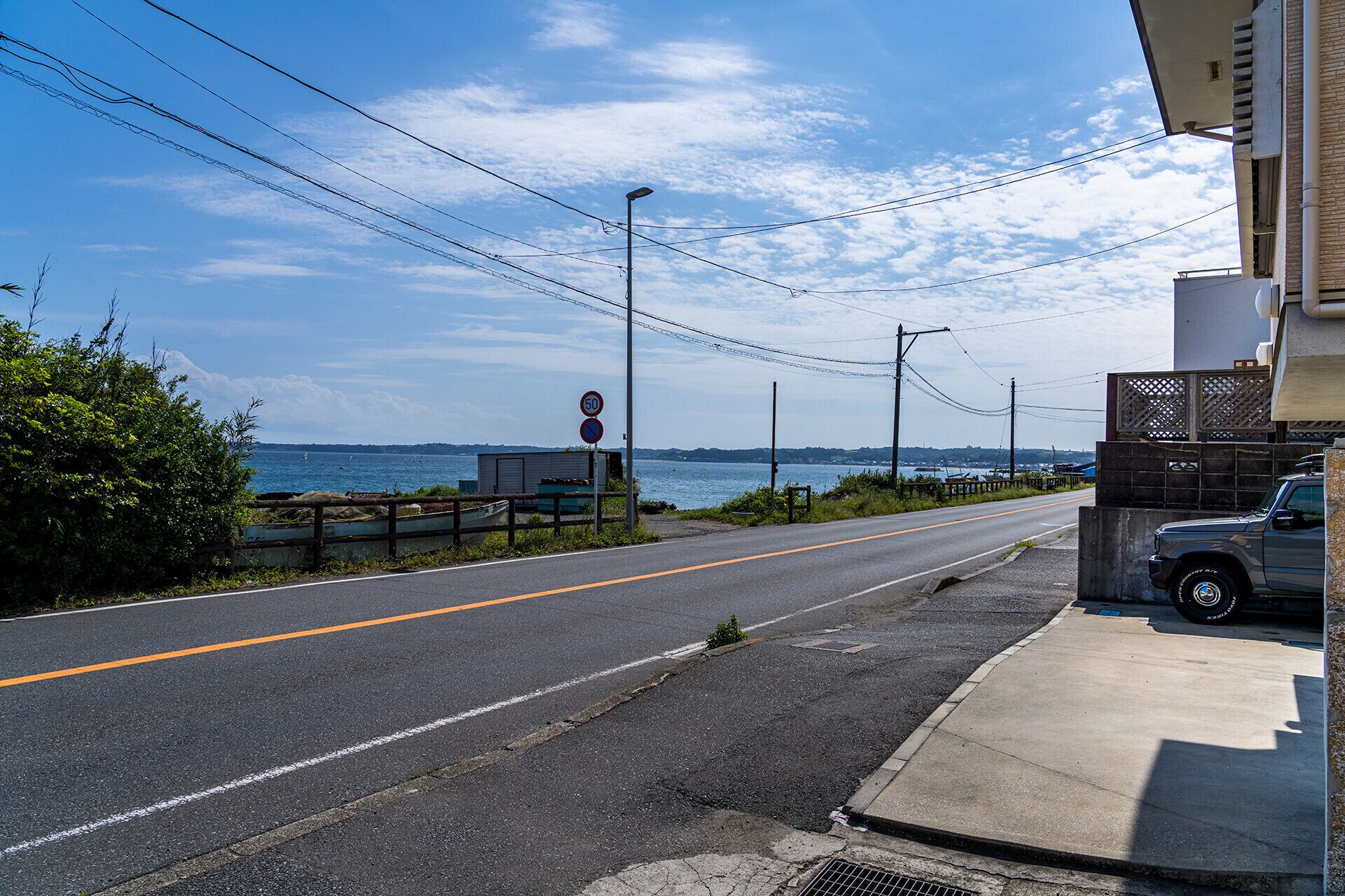 Uma estrada costeira com placa de limite de velocidade, um caminhão estacionado e vista para o mar.