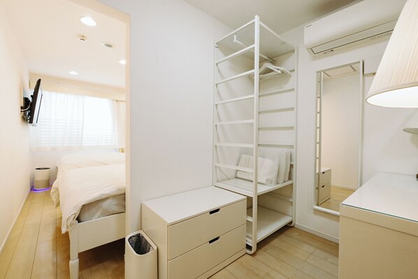 Un dormitorio con una cama, un armario blanco, un espejo y una mesita de noche.