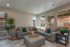 A living room with a sectional sofa, a coffee table, and a potted plant.