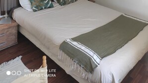 A neatly arranged bedroom with a bed, pillows, a bedside lamp, a wall-mounted picture, and a hanging light fixture. - Sea view luxury residence (Corse)