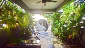 Un espace intérieur lumineux, baigné de soleil, avec un sol à carreaux, un symbole yin-yang et de nombreuses plantes vertes de chaque côté.