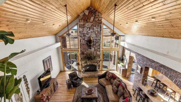 A spacious living area with a stone fireplace, wooden ceiling, and large windows offering views of the outdoors. - Gorgeous Estate Home on 186 Acre Ranch only minutes from Colorado Springs or AFA (Colorado Springs)