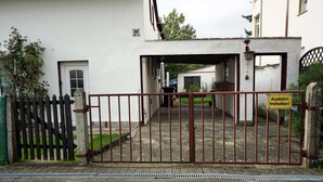 Une entrée fermée par un portail mène à un immeuble sur lequel est apposée une pancarte indiquant un espace de stationnement.