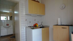 Une cuisine de taille réduite avec des meubles blancs, un évier et un petit réfrigérateur.