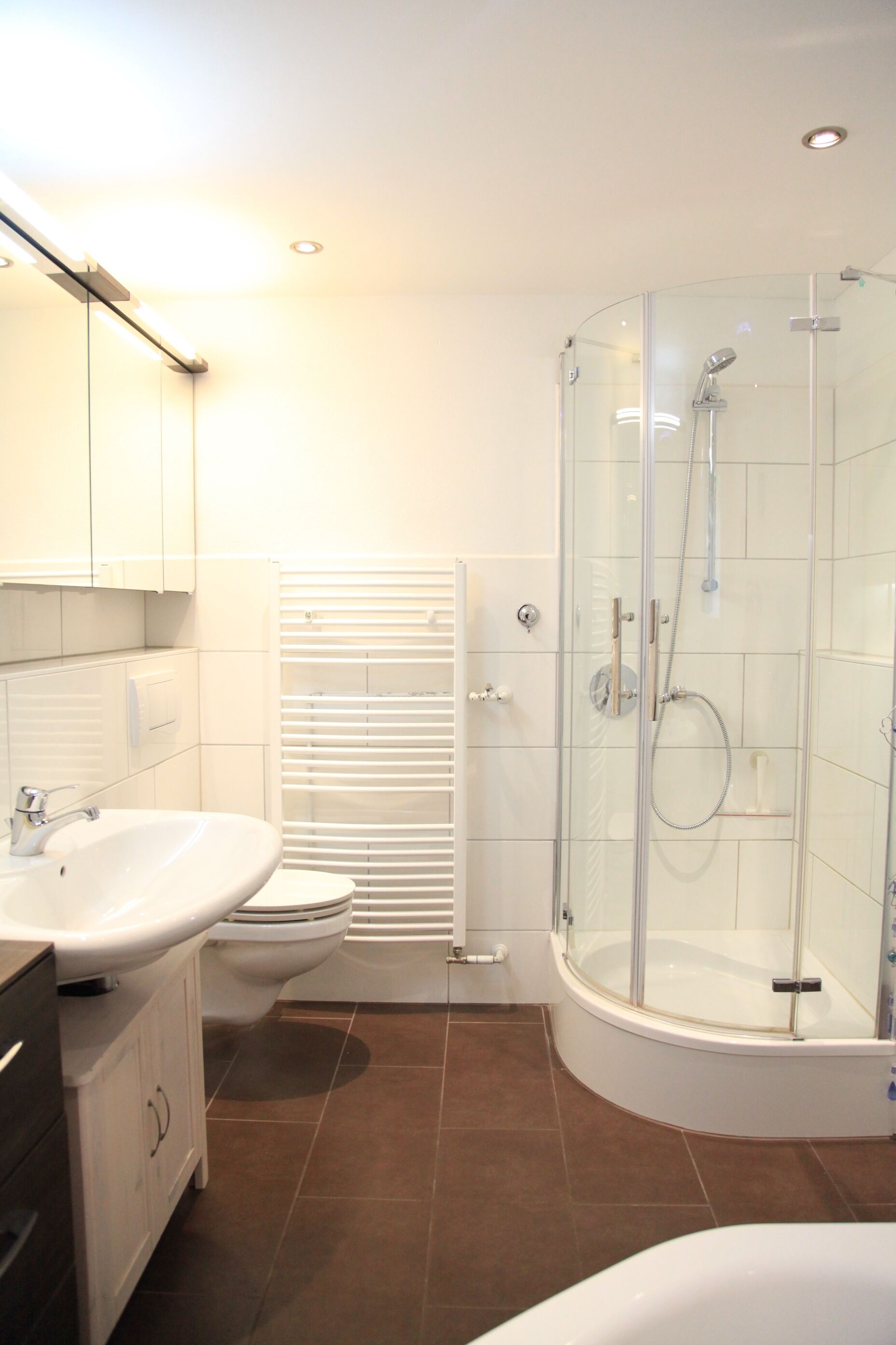 Une salle de bain moderne avec une douche à parois de verre, un lavabo blanc et des toilettes.